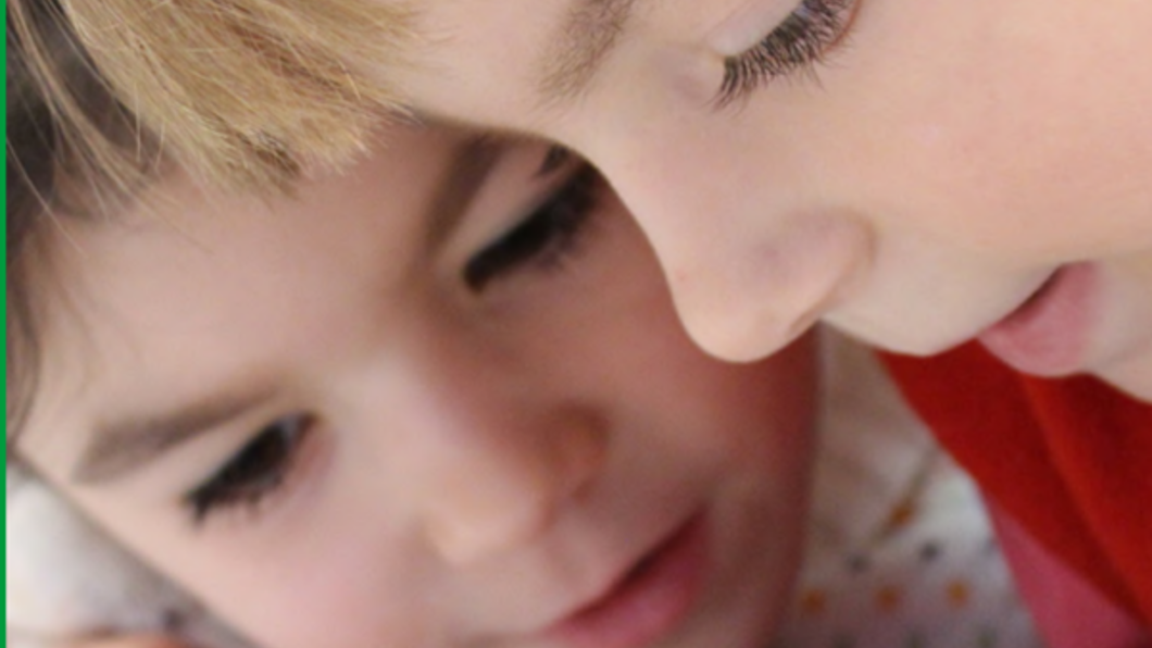 Foto van twee kinderen die in een schriftje tekenen