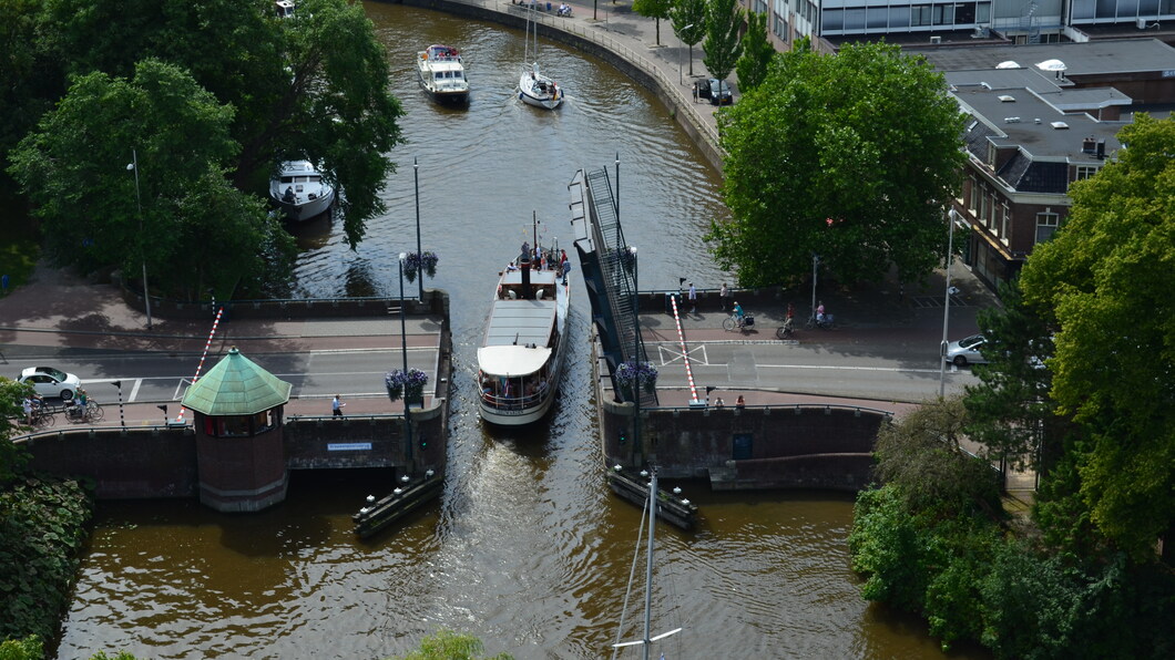 Foto van een schip dat onder de Vrouwenpoortsbrug vaart, genomen vanaf de Oldehove